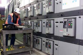 An Electrician Verifies that One of the Motor Controls that will Operate a Piece of Equipment in the Silos 1 and 2 Treatment Facility Works Correctly.
8,900 cubic yards of high activity low-level waste material will be removed from Silos 1 and 2, processed and shipped off site for disposal. This material was generated from 1951 to 1960 as a waste by-product from the processing of high-grade uranium ores. The Silos 1 and 2 material, also known as K-65 material, contains radium and throium radioclides. Waste Retrieval Project will consist of six major systems; Silos Waste Retrieval System; Decant Sump Waste Retrieval System; Transfer Tank Area; Transfer Tank Waste Retrieval System; Radon Control System; and the Full Scale Mock-Up System. Once the waste is removed from the silos it will then be stabilized with a formulation of flyash and Portland cement before being containerized for shipment. 
Keywords: Fernald Closure Project Fernald Green Salt Plant, Feed Materials Production Center, Fernald, Ohio (FEMP)