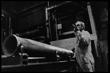 Pickled Extrusion Inspection
An inspector Okays the new extrusion. It has been cooled in air, quenched in water, and given a bath in acid. At this point it is referred to as a "pickled extrusion." 

Reactive Metals, Incorporated, Ashtabula, Ohio. June 19,1984. 
Keywords: Reactive Metals, Incorporated, Ashtabula, Ohio